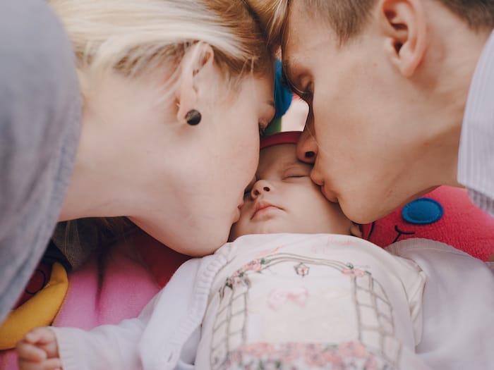 Parents Kissing Baby